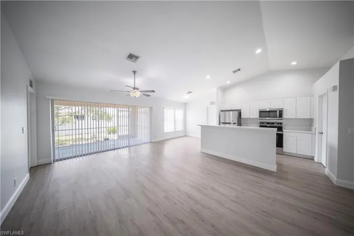 Unfurnished living room featuring light wood-style floors, a ceiling fan, high vaulted ceiling, and recessed lighting