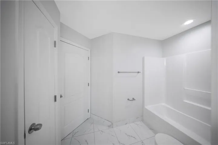 Full bathroom featuring light marble finish flooring, shower / bath combination, and recessed lighting