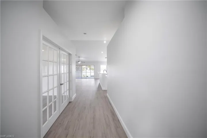 Hallway featuring light wood-type flooring, french doors, and recessed lighting