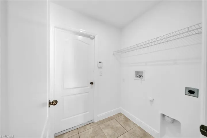 Washroom with electric dryer hookup, hookup for a washing machine, light tile patterned flooring, and hookup for a gas dryer