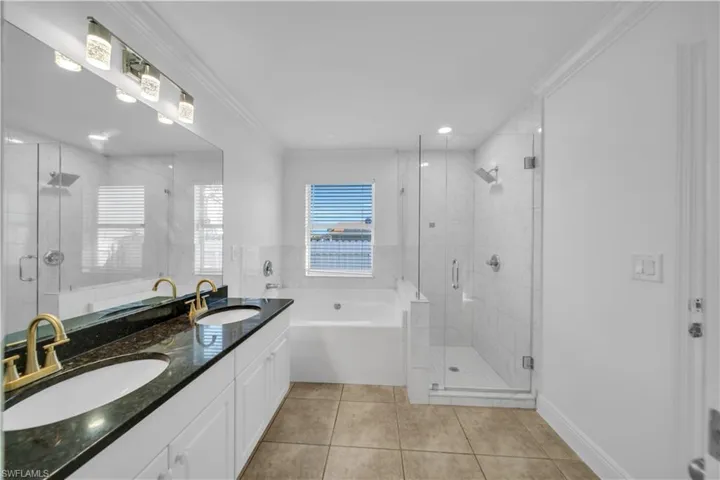 Bathroom with a garden tub, tile patterned floors, double vanity, a stall shower, and ornamental molding