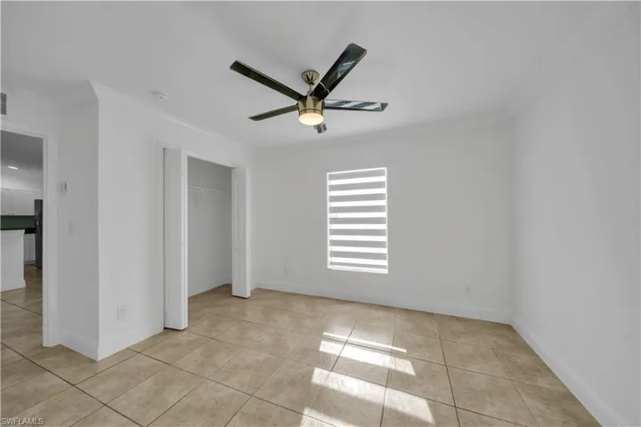 Unfurnished bedroom featuring light tile patterned floors, ornamental molding, a closet, and a ceiling fan