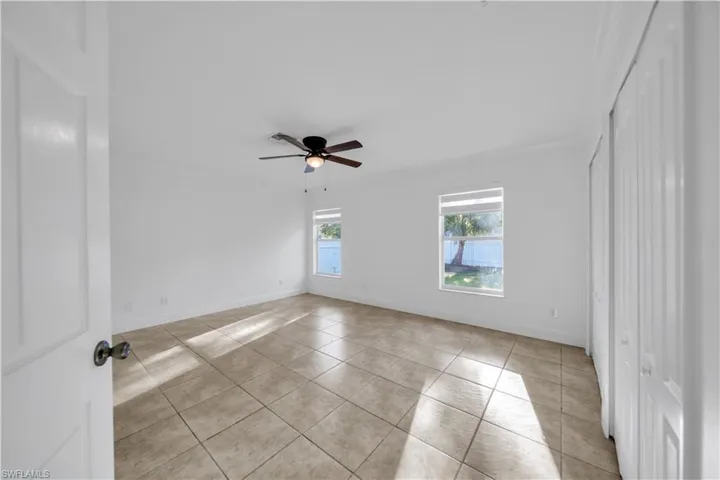 Empty room featuring light tile patterned flooring and ceiling fan