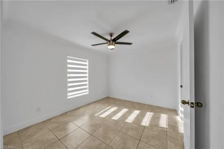 Spare room featuring ornamental molding, ceiling fan, and light tile patterned floors