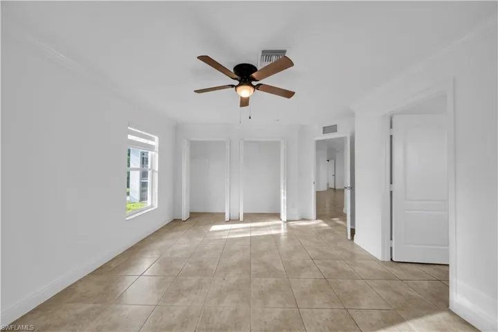 Spare room with a ceiling fan, light tile patterned floors, and ornamental molding