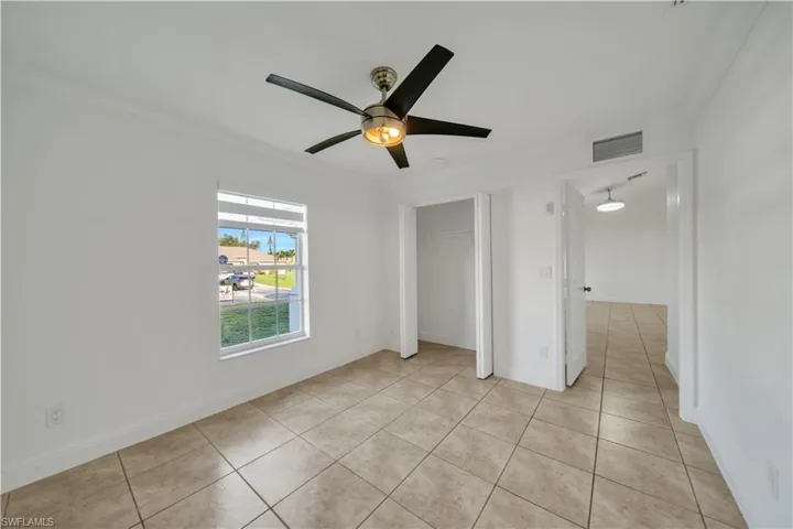 Unfurnished bedroom featuring ornamental molding, light tile patterned flooring, a closet, and a ceiling fan