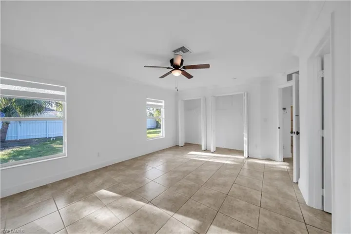 Unfurnished room featuring a ceiling fan, ornamental molding, and light tile patterned flooring