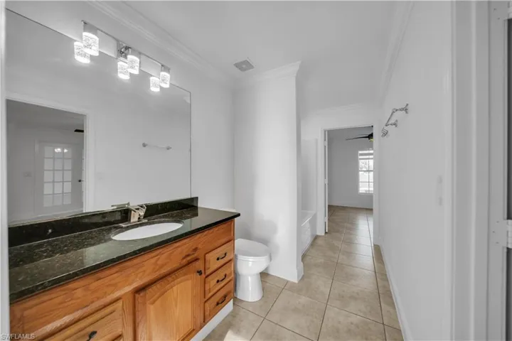 Bathroom with tile patterned floors, vanity, and crown molding
