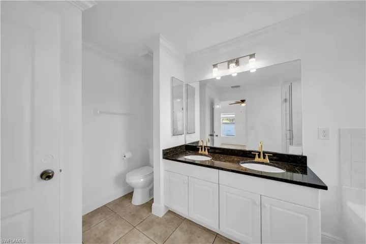 Bathroom with double vanity, crown molding, ceiling fan, tile patterned flooring, and a shower