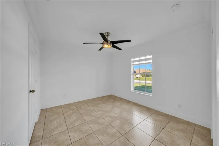 Empty room featuring ornamental molding, light tile patterned floors, and ceiling fan