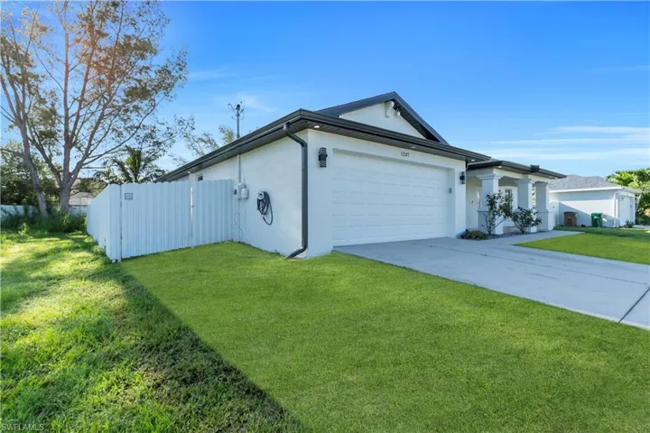 View of home's exterior featuring stucco siding, a garage, concrete driveway, and a gate