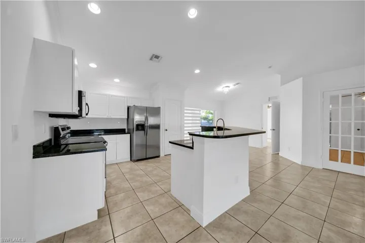 Kitchen with appliances with stainless steel finishes, dark countertops, light tile patterned floors, white cabinetry, and recessed lighting