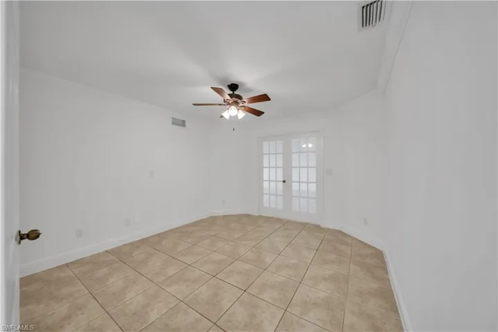 Empty room with a ceiling fan, ornamental molding, and light tile patterned flooring