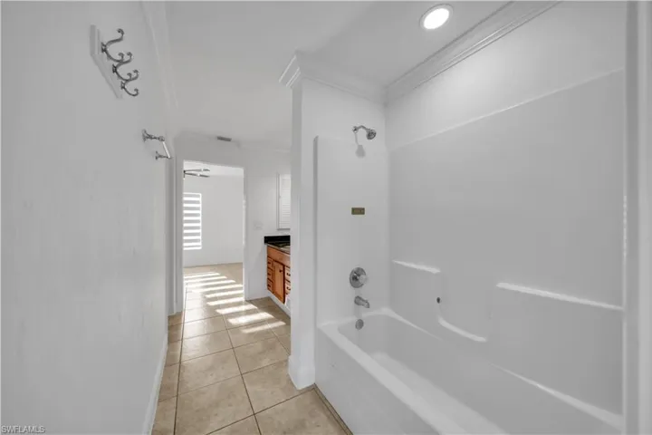Bathroom featuring shower / bath combination, ornamental molding, vanity, and tile patterned flooring