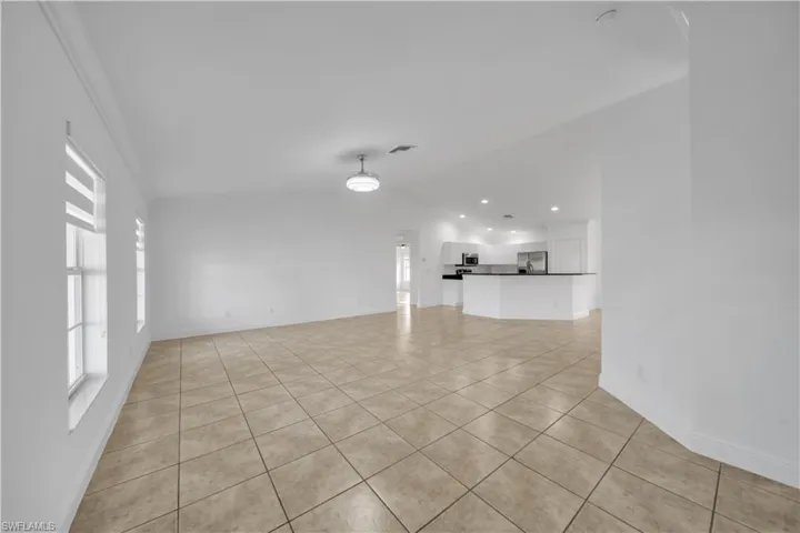 Unfurnished living room featuring light tile patterned floors, plenty of natural light, lofted ceiling, and recessed lighting