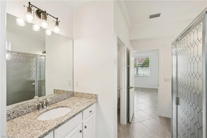 Full bath with a stall shower, ornamental molding, vanity, and light tile patterned floors