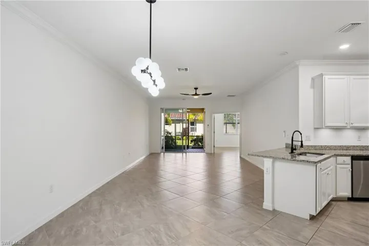 Kitchen with white cabinetry, ornamental molding, light stone counters, ceiling fan, and a peninsula
