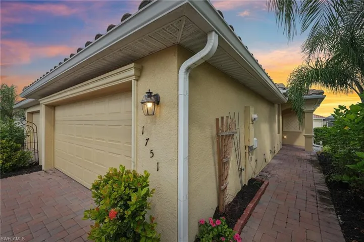 View of side of home with stucco siding, decorative driveway, and an attached garage