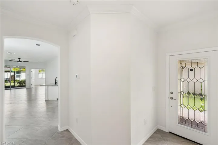 Entryway with a ceiling fan, ornamental molding, arched walkways, and light tile patterned floors
