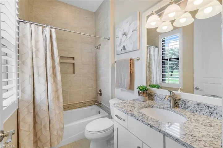 Full bathroom with shower / tub combo with curtain, vanity, and toilet