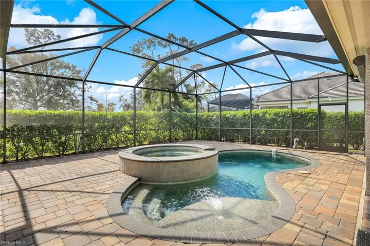 View of swimming pool featuring glass enclosure, an in ground hot tub, and a patio