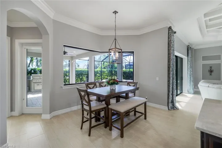 Dining room featuring crown molding, light tile patterned flooring, and ceiling fan with notable chandelier