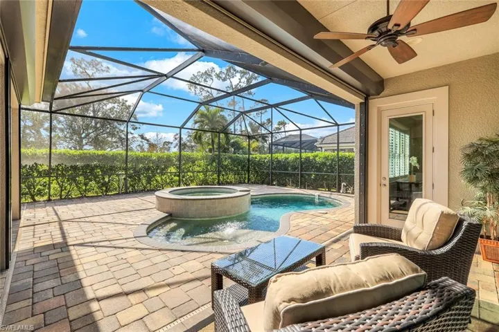 View of swimming pool featuring an in ground hot tub, glass enclosure, ceiling fan, and a patio area