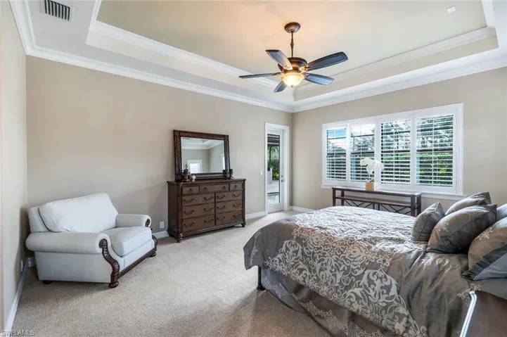 Carpeted bedroom with access to exterior, a tray ceiling, ceiling fan, and crown molding