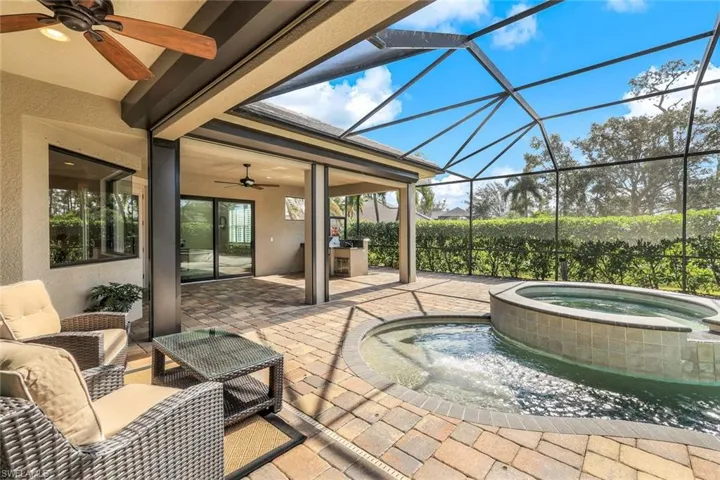 View of patio / terrace with an in ground hot tub, glass enclosure, and ceiling fan