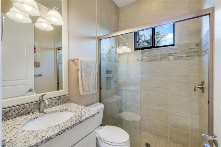 Bathroom with vanity, a shower with shower door, and toilet
