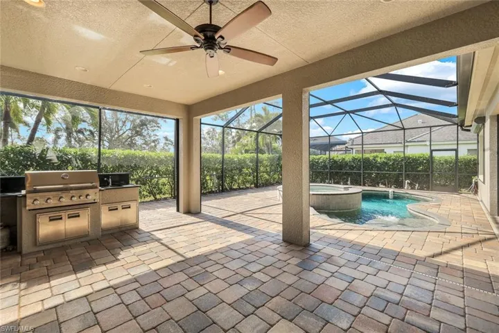 View of patio with glass enclosure, area for grilling, ceiling fan, and exterior kitchen