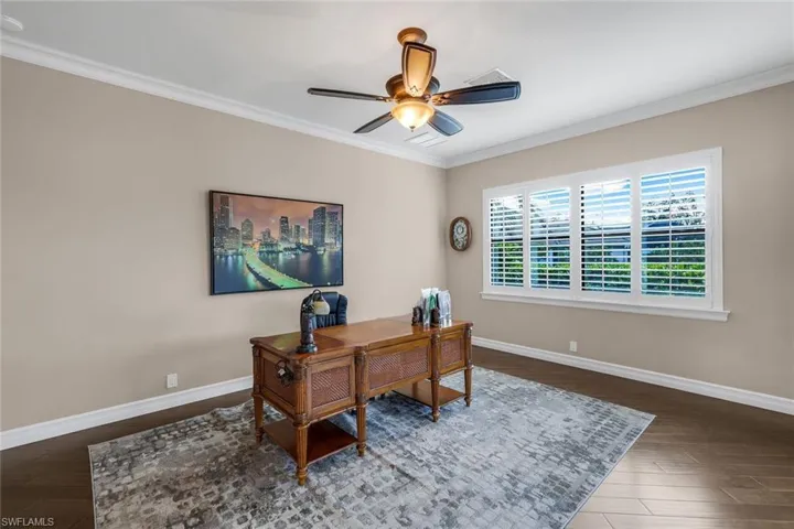 Office featuring dark hardwood / wood-style flooring, ceiling fan, and ornamental molding