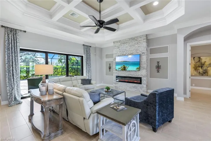 The space flows effortlessly toward sliding glass doors that open to a screened lanai, revealing a sparkling swimming pool and spa. This seamless indoor-outdoor connection enhances the room's functionality and offers a perfect retreat for relaxation or entertaining.