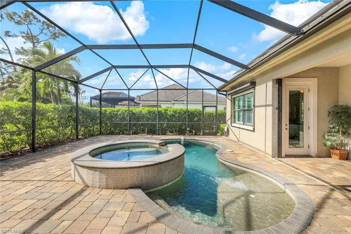 View of pool featuring an in ground hot tub, a patio, and glass enclosure