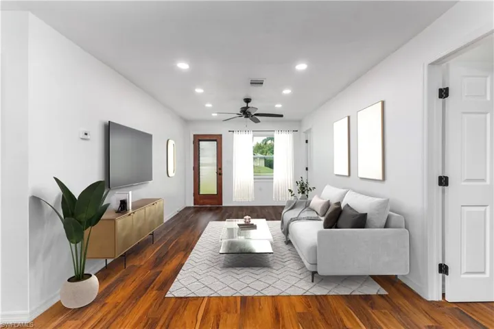 Living room with ceiling fan and dark hardwood / wood-style floors