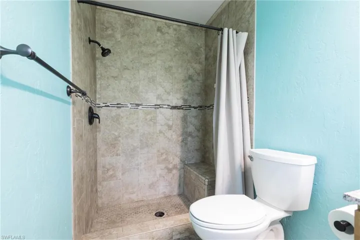 Bathroom featuring tiled shower and toilet