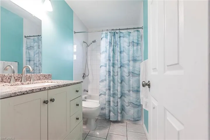 Full bathroom with shower / bath combo with shower curtain, vanity, and toilet