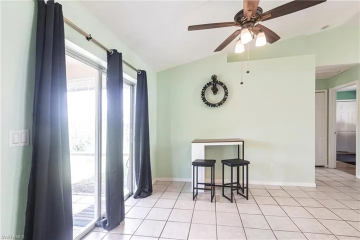 Dining area featuring vaulted ceiling, a ceiling fan, light tile patterned floors, and baseboards