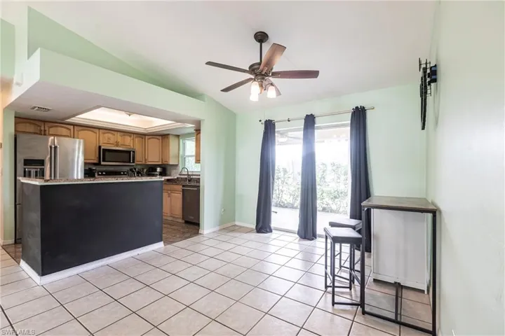 Kitchen featuring appliances with stainless steel finishes, a ceiling fan, vaulted ceiling, a sink, and light tile patterned flooring