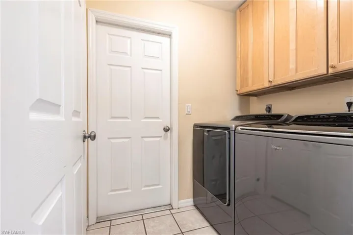 Laundry room with cabinet space, washing machine and clothes dryer, light tile patterned flooring, and baseboards