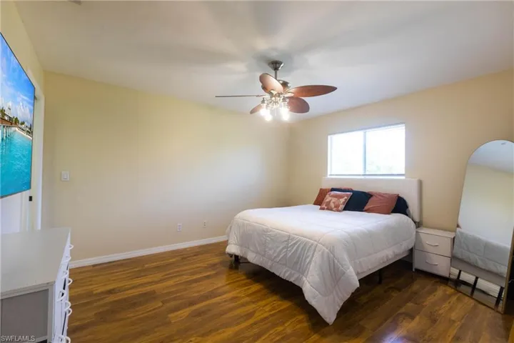 Bedroom with dark wood-style flooring, a ceiling fan, and baseboards