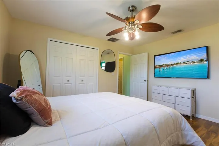 Bedroom featuring dark wood-type flooring, baseboards, ceiling fan, and a closet