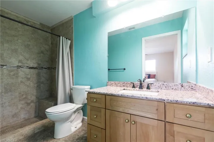 Full bath featuring vanity, toilet, and a tile shower