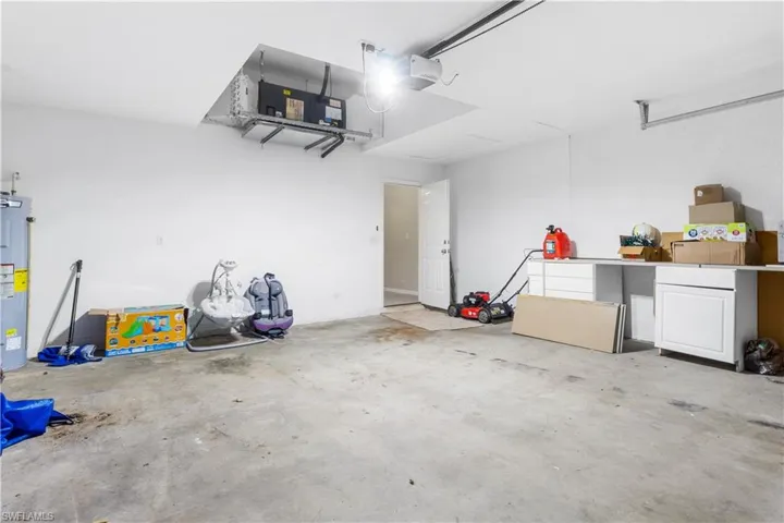 Garage featuring electric water heater and a garage door opener