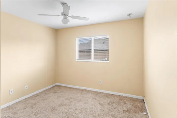 Carpeted empty room featuring baseboards and ceiling fan