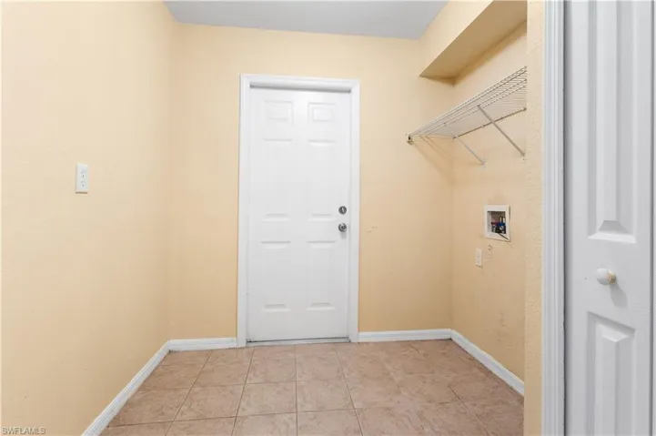Washroom with light tile patterned flooring and hookup for a washing machine
