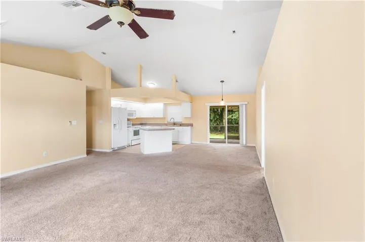 Unfurnished living room with light colored carpet, ceiling fan, and high vaulted ceiling