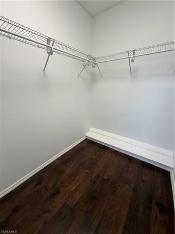 Walk-in closet featuring wood-finish flooring, white baseboards, and white wire shelving