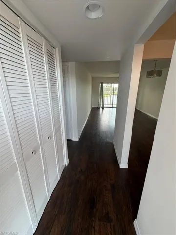 Hallway featuring wood-finish flooring, white baseboards, and bright white walls