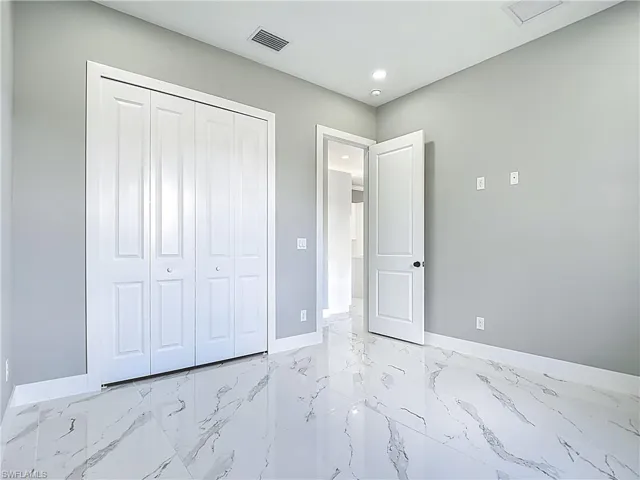 Unfurnished bedroom featuring light marble finish flooring, recessed lighting, and a closet